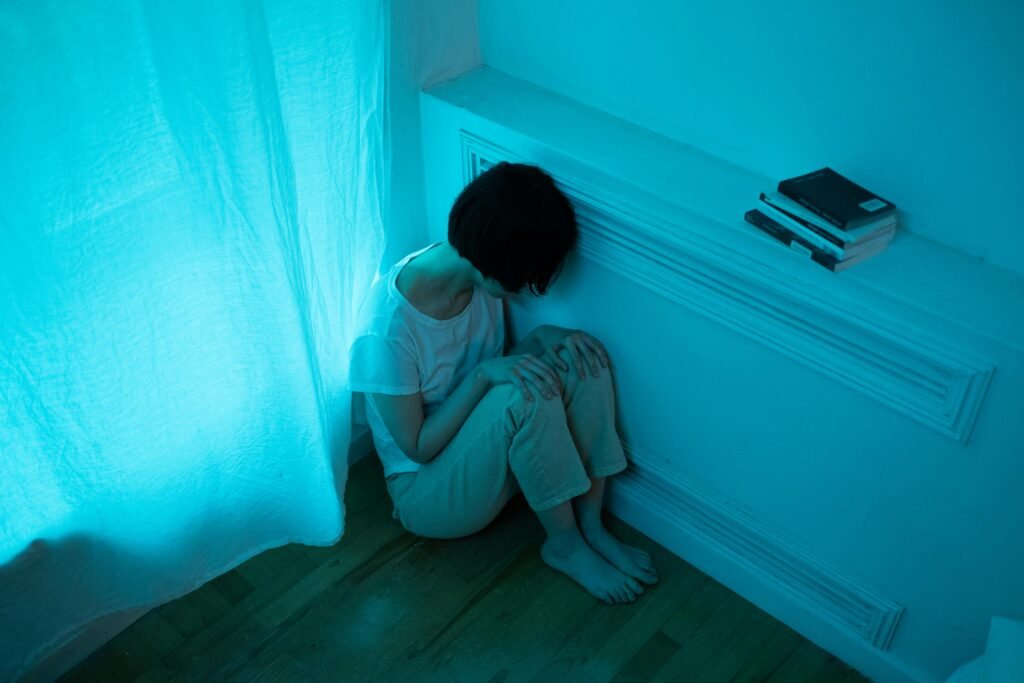 A Woman Sitting on the Floor while Leaning on the Wall